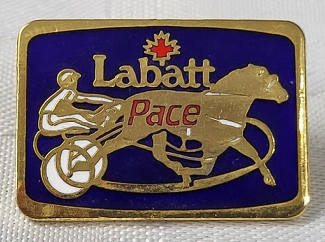 A metal pin depicting a horse and driver with Labbatt Pace inscribed