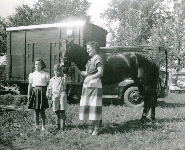 A woman holds a horse alongside her son and daughter