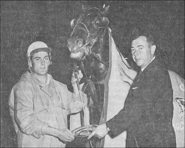 Two men posing, holding a plate trophy and a horse 