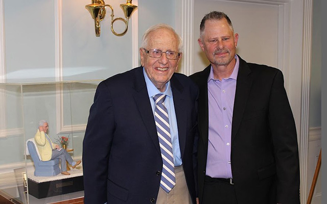Two men in suits pose for a photo