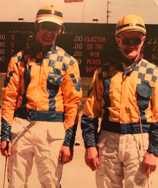Two men in blue and gold driving colours
