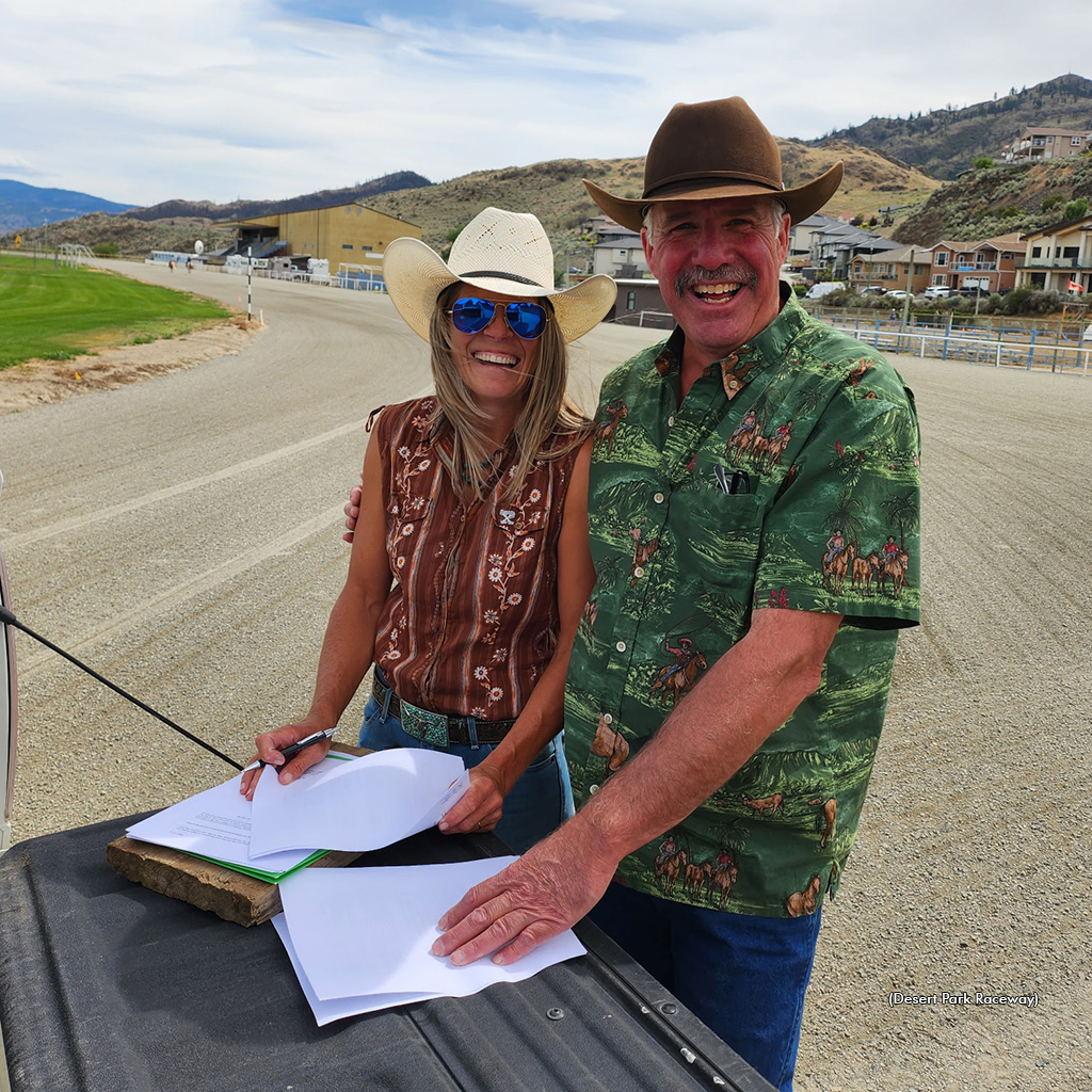 Rebekka Lim and Kelly MacMillan sign an agreement on the tailgate of a truck on the Desert Park racetrack