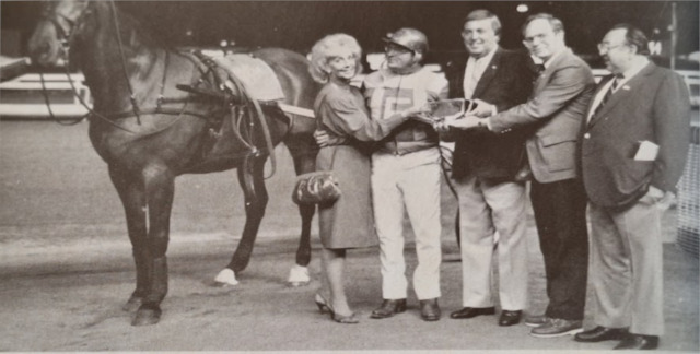 A group of people next to a horse in the winner's circle
