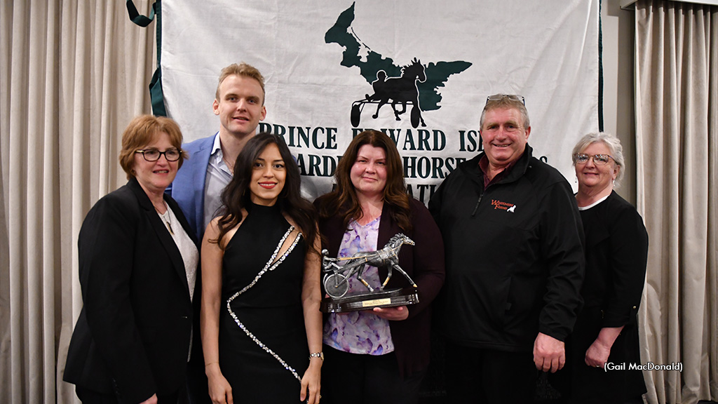 A group of people gather to accept a horse trophy