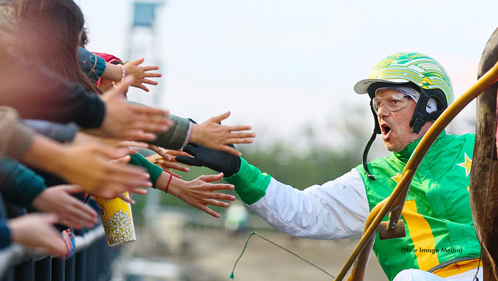 Jody Jamieson gets high fives from harness racing fans at the rail