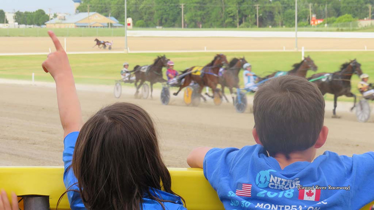Kids cheering on horses in a race at Grand River Raceway